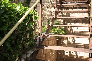 View of old metal stairs with handrails near brick wall outdoors