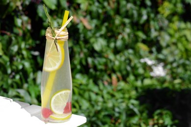 Photo of Refreshing tasty lemonade served in glass bottle on white wooden surface. Space for text