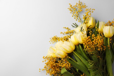 Bouquet with beautiful tulips and mimosa flowers on light background, top view. Space for text