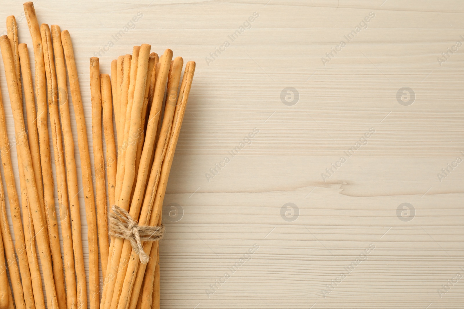 Photo of Delicious grissini sticks on white wooden table, flat lay. Space for text