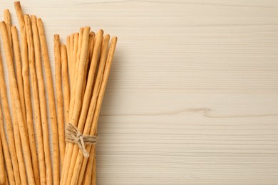 Delicious grissini sticks on white wooden table, flat lay. Space for text