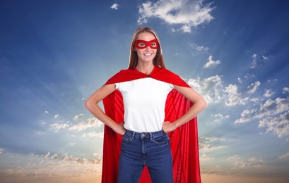 Image of Confident woman wearing superhero cape and mask against blue sky with clouds