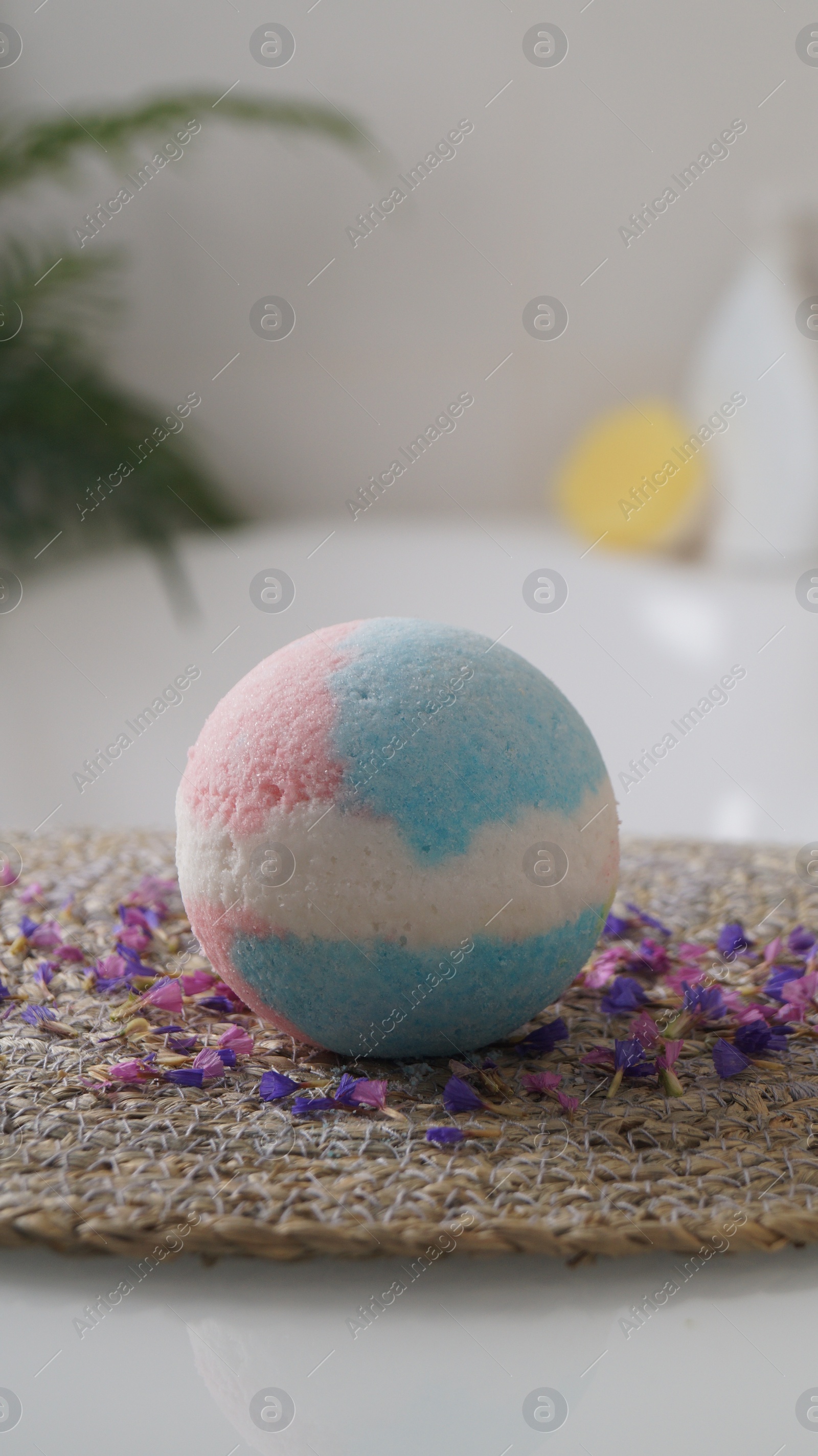 Photo of Beautiful bath bomb on wicker mat indoors