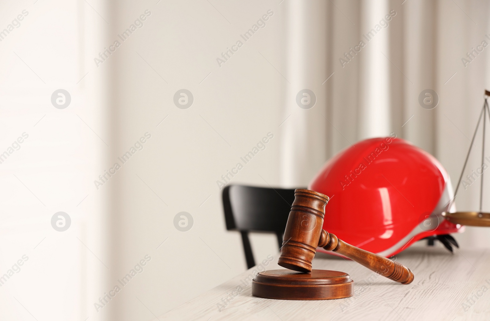 Photo of Law concept. Gavel and red hard hat on white wooden table, space for text