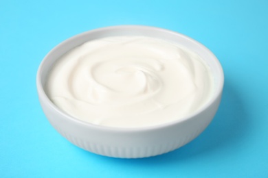 Bowl of sour cream on light blue background