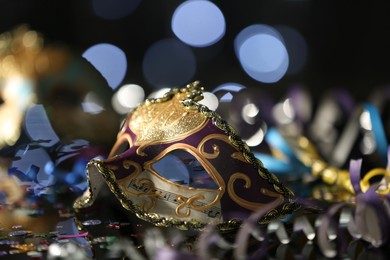 Photo of Beautiful carnival mask on table against blurred lights