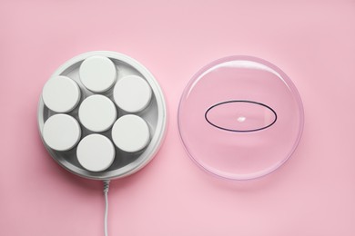 Modern yogurt maker with jars on pink background, flat lay