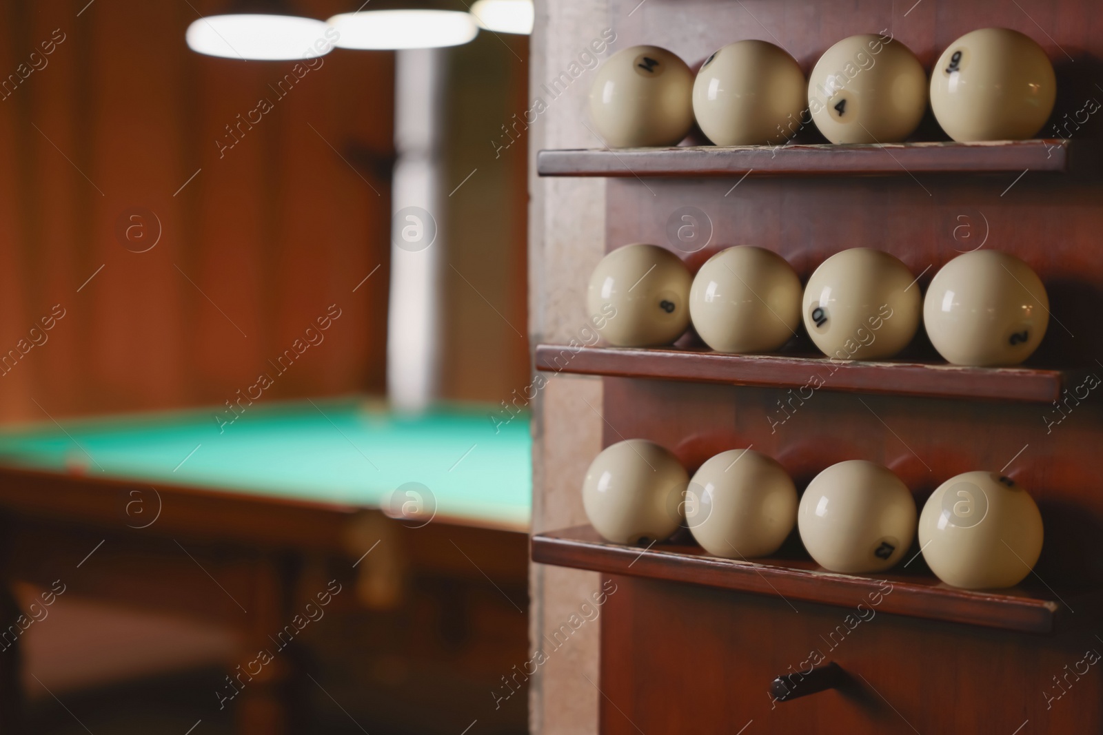 Photo of Set of billiard balls on wooden shelves indoors, closeup. Space for text