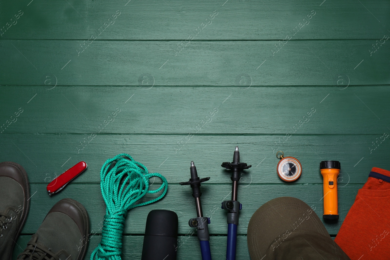 Photo of Flat lay composition with trekking poles and other hiking equipment on green wooden background, space for text