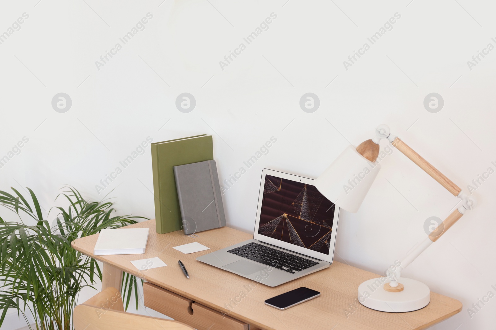 Photo of Cozy workspace with laptop, smartphone and lamp on wooden desk at home