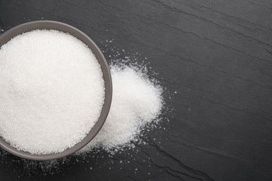 Photo of Granulated sugar on black table, top view. Space for text