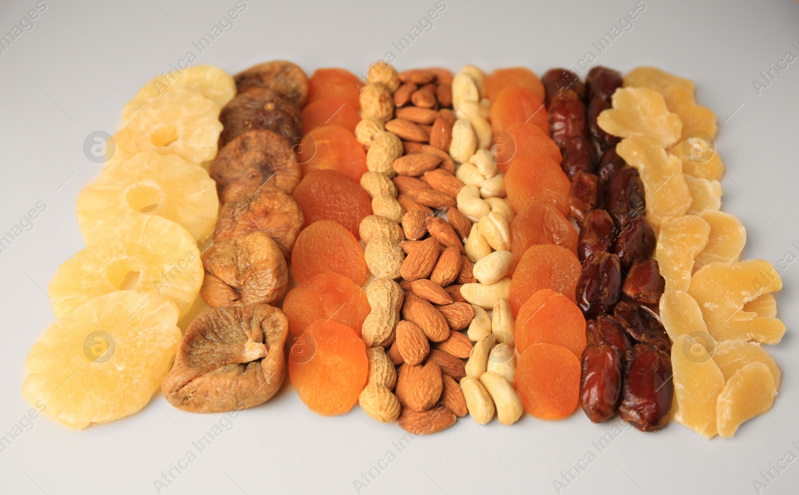 Photo of Different tasty nuts and dried fruits on beige background