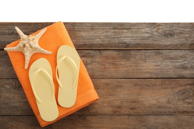 Photo of Wooden surface with beach towel, starfish and flip flops on white background, top view. Space for text