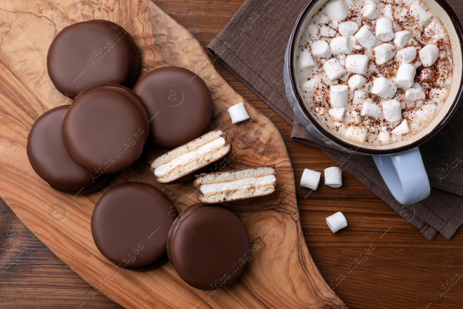 Photo of Tasty choco pies and cocoa with marshmallows on wooden table, flat lay