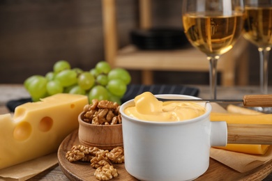 Pot of tasty cheese fondue and products on wooden table