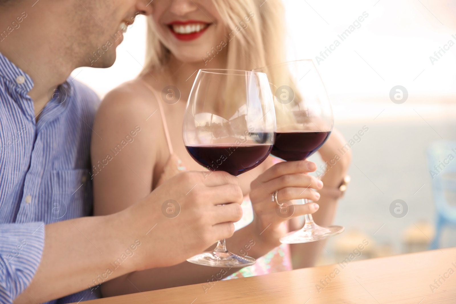 Photo of Young romantic couple with glasses of red wine at table