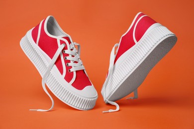Photo of Pair of red classic old school sneakers on orange background