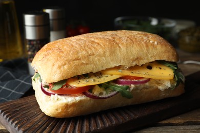 Photo of Delicious sandwich with fresh vegetables and cheese on wooden table