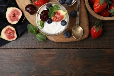 Glass with yogurt, berries and mint on wooden table, top view. Space for text