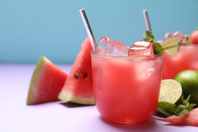 Photo of Tasty watermelon drink on violet table, closeup. Space for text