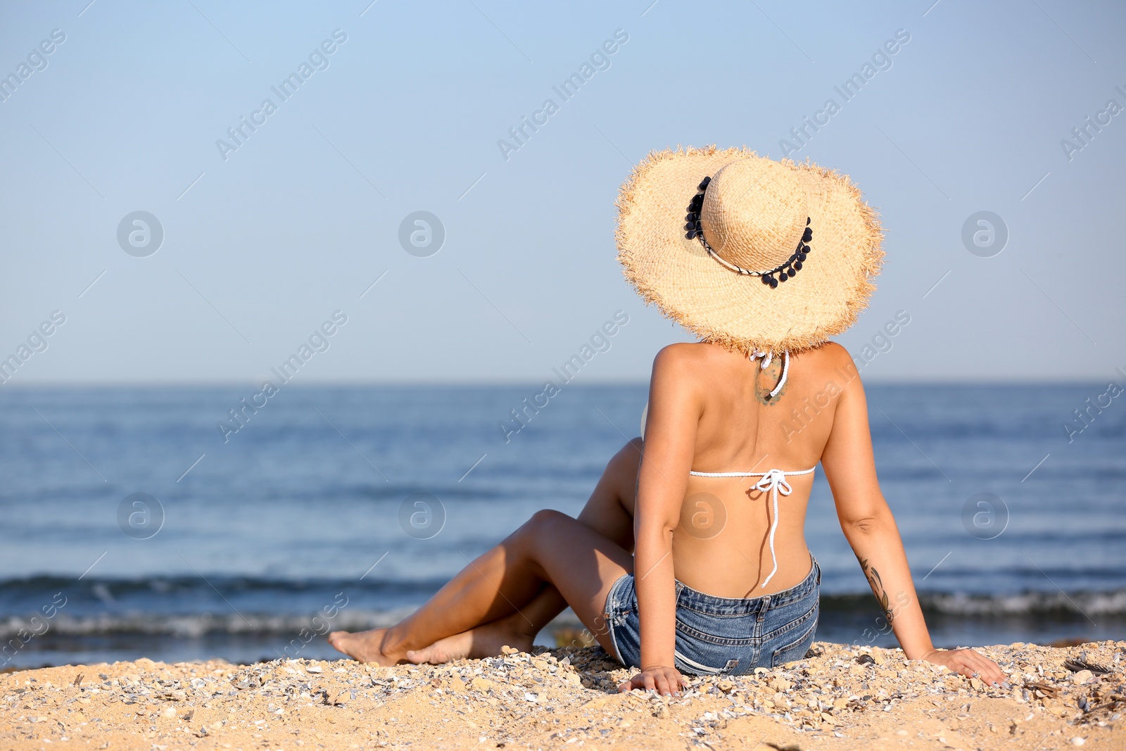 Photo of Young woman in straw hat on beach. Space for text