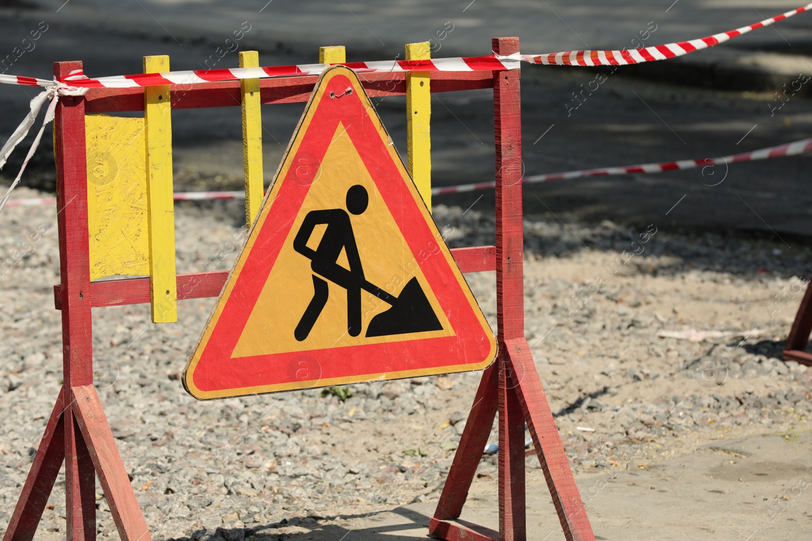 Photo of Wooden barricade with road construction sign on city street. Repair works