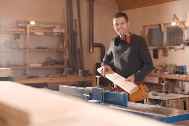 Photo of Professional carpenter working with surface planer in workshop