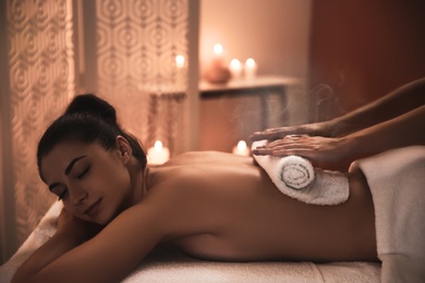 Image of Young woman receiving hot towel massage in spa salon