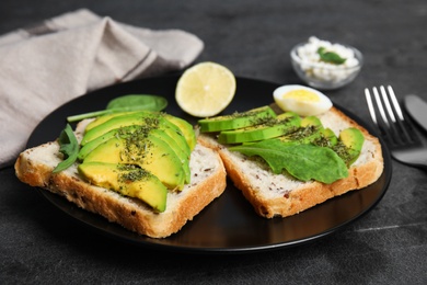 Photo of Tasty avocado toasts served on black table, closeup