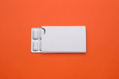 Photo of Blister with chewing gums on orange background, top view