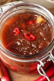 Photo of Tasty rhubarb sauce in glass jar on table, closeup view