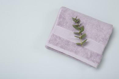 Violet terry towel and eucalyptus branch on light grey background, top view. Space for text