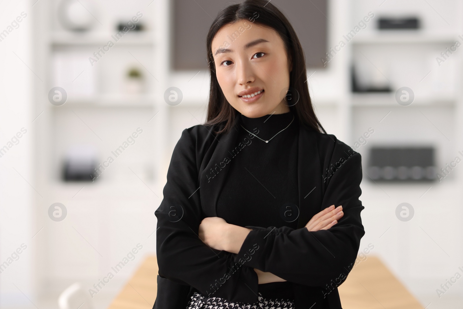 Photo of Portrait of smiling businesswoman with crossed arms in office