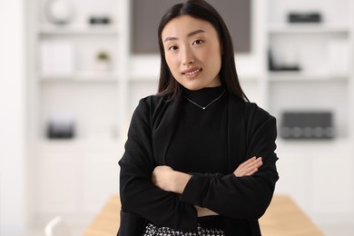 Portrait of smiling businesswoman with crossed arms in office