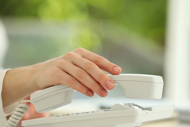 Photo of Assistant taking telephone handset on blurred background, closeup