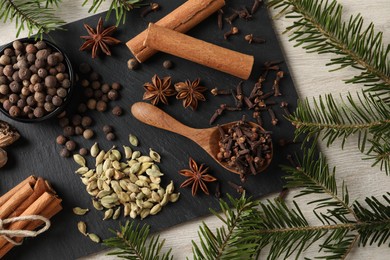 Photo of Different spices and fir branches on wooden table, flat lay