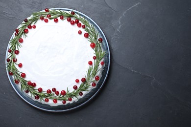 Photo of Traditional Christmas cake decorated with rosemary and cranberries on dark grey table, top view. Space for text