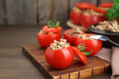 Photo of Delicious stuffed tomatoes with minced beef, bulgur and mushrooms on wooden table, closeup. Space for text