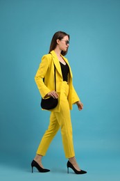 Photo of Fashionable young woman with stylish bag on light blue background