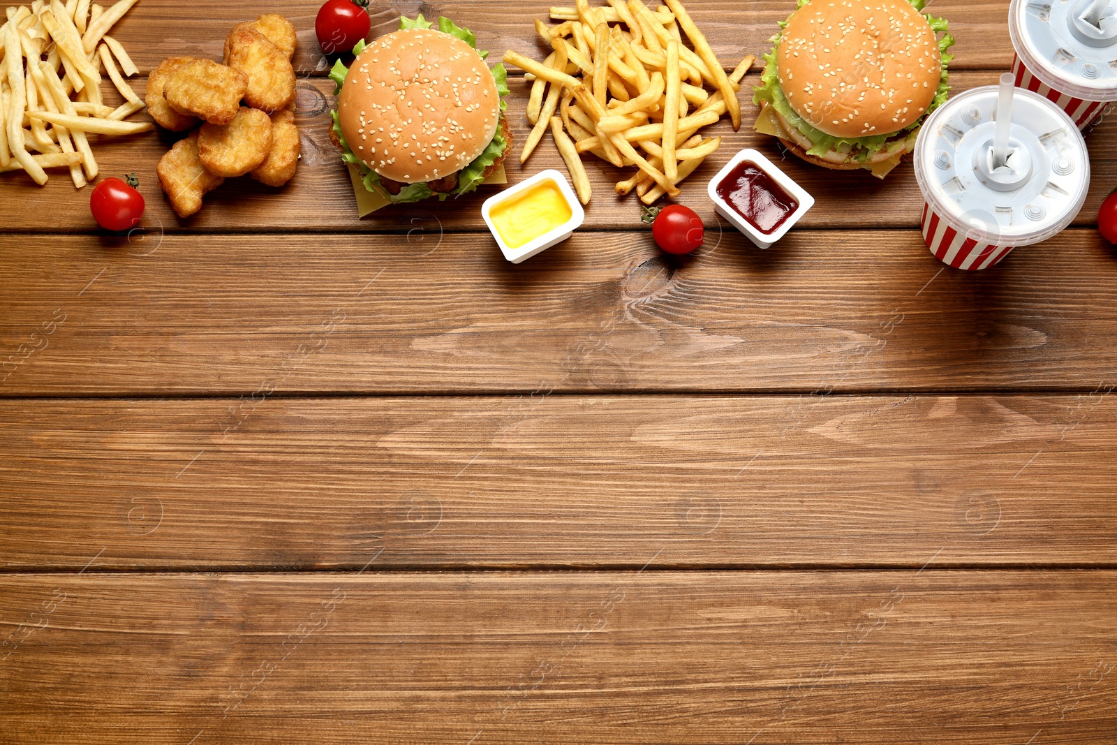 Photo of Flat lay composition with delicious fast food menu on wooden table. Space for text