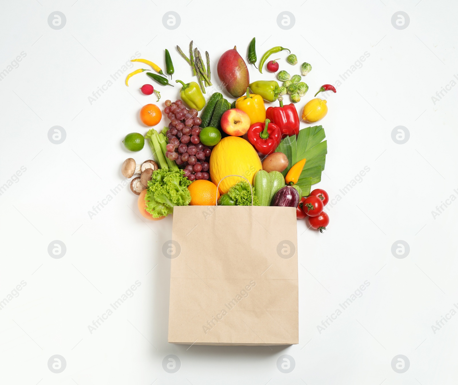 Photo of Paper bag with assortment of fresh organic fruits and vegetables on white background, top view