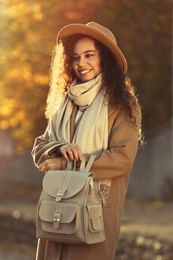 Photo of Portrait of beautiful African-American woman with stylish beige backpack on city street