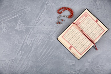 Photo of Muslim prayer beads, Quran and space for text on grey background, top view