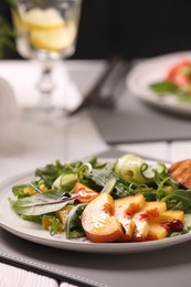 Delicious salad with peach slices on table