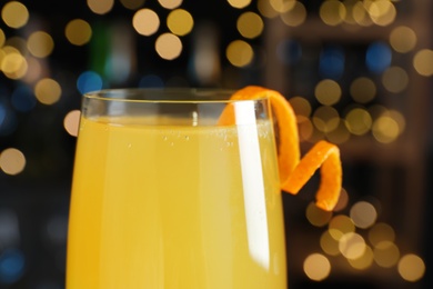 Photo of Mimosa cocktail with garnish against blurred lights, closeup