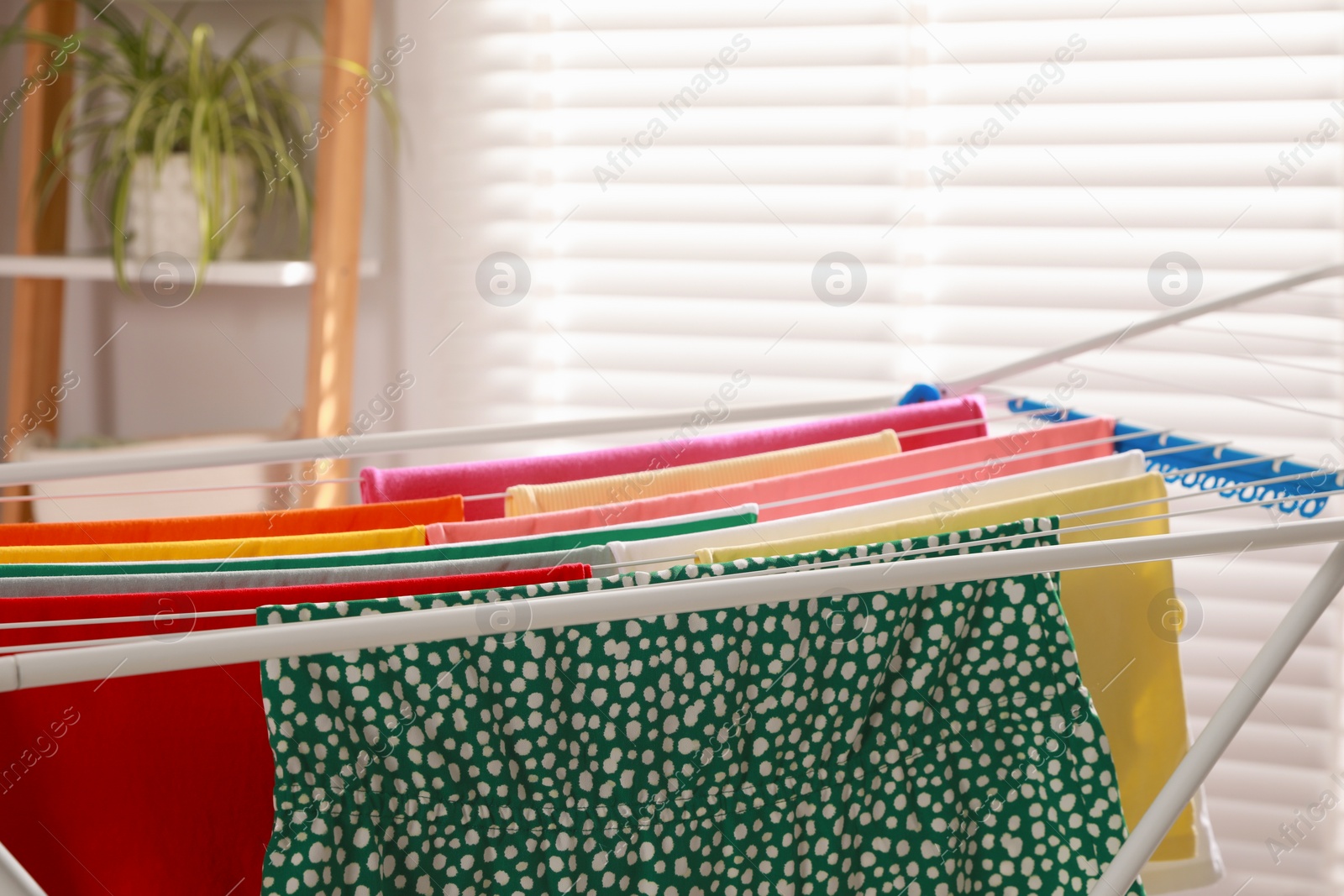 Photo of Different apparel drying on clothes airer indoors