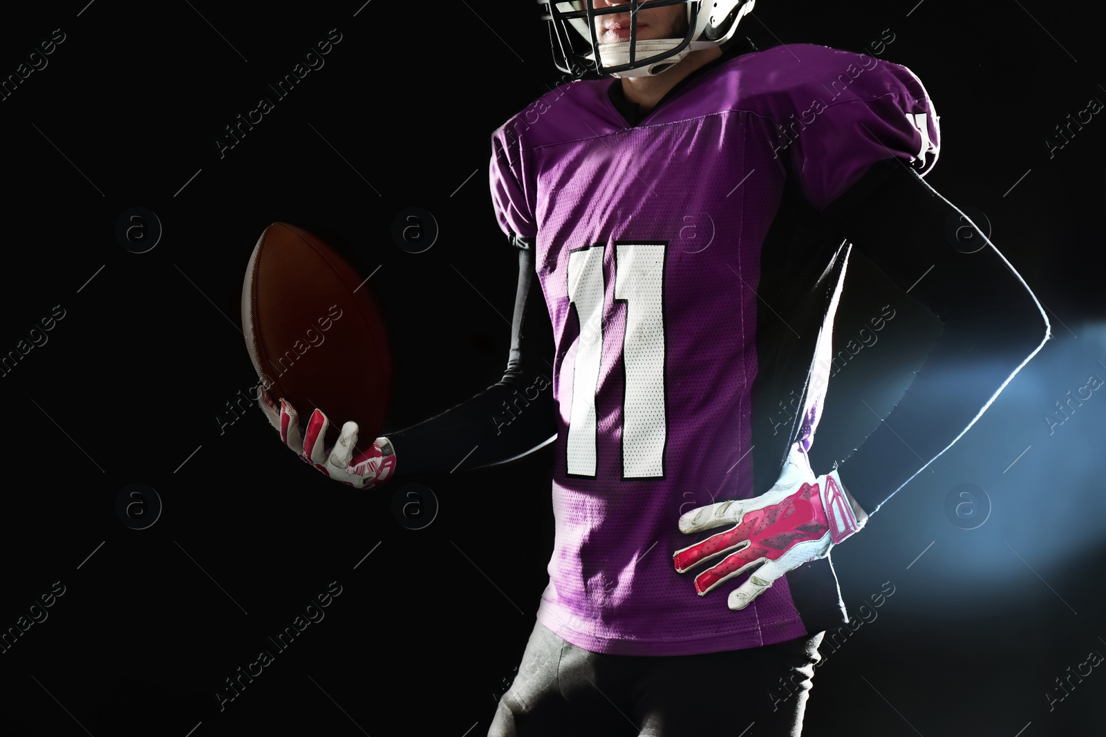 Photo of American football player with ball on dark background