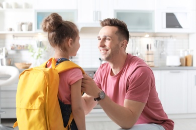 Photo of Young man helping his little child get ready for school at home