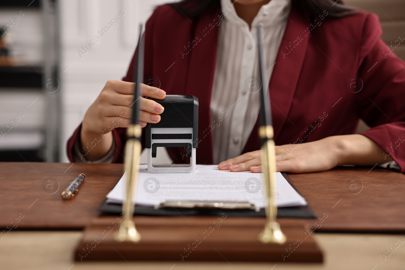 Photo of Notary stamping document at table in office, closeup