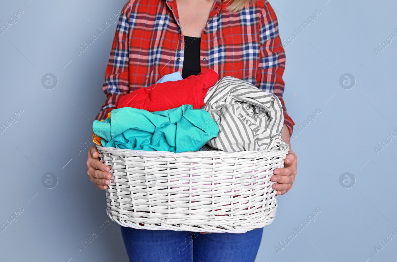 Photo of Woman holding laundry basket with dirty clothes on color background